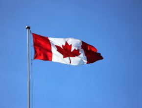 Canadian flag waving proudly against a clear blue sky in Victoria, BC.