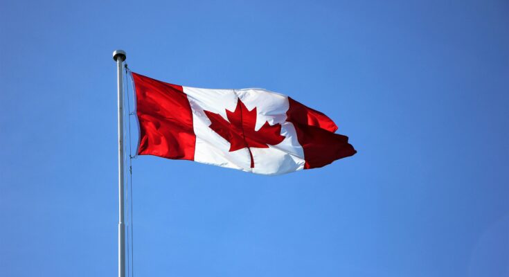 Canadian flag waving proudly against a clear blue sky in Victoria, BC.